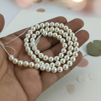 6mm Round Shell Pearl Beads with a smooth high-gloss finish, perfect for delicate bracelets, necklaces, and premium DIY jewelry designs. Uniform, durable, and elegant. Sold Per Line 67~68 beads